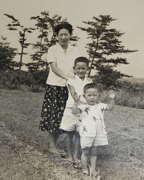 _-1 | Seattle’s Japanese Community News – North American Post Asian mother walking along a dirt path with her two young sons outdoors, tall trees in the background.