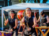 Living Traditions, a New Multicultural Art Series Debuts at Bellevue Arts Fair Three taiko drummers in black outfits perform under a white canopy, with a large drum in the foreground and wooden stands nearby.