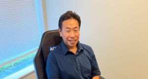 Man in a blue shirt sits in a specialized therapy chair, with a leg compression/cooling device strapped to his right leg and connected control panels nearby.