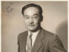 Minoru Yasui Featured at the Barack Obama Presidential Center Portrait of a man in a suit and glasses, standing with hands in pockets, posing for a formal studio photo; handwritten notes appear in the corners.
